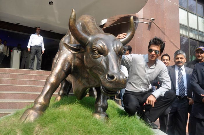 Shah Rukh Khan poses with the bronze statue of a bull after the listing ceremony.