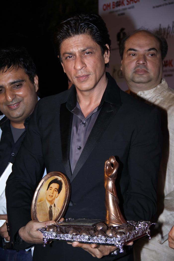 Shah Rukh holds a souvenir with Dilip Kumar's image on it.