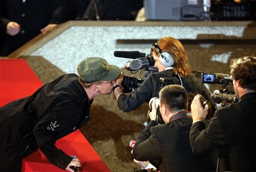 U2's Bono, left, kisses the wrist of an unidentified member of the media during a perfromance for the screening of the film U2 3D, at the 60th International film festival in Cannes.