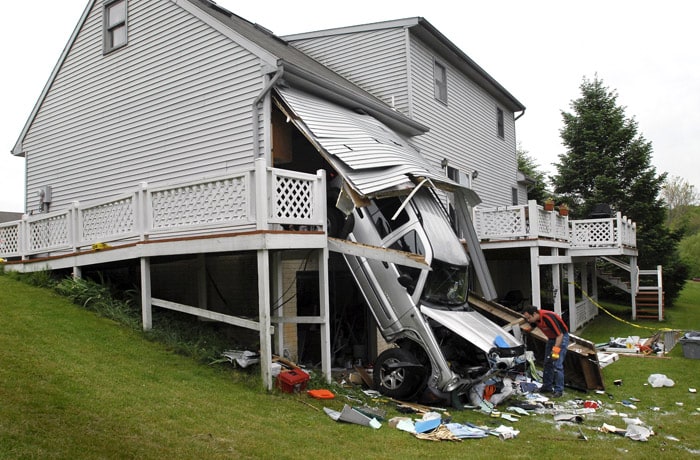 A tow truck operator tries to figure out how to tow a Jeep Liberty after the driver drove through the back wall of his own garages, falling one story to the ground Monday, on May 17, 2010, in Lancaster, Pennsylvania. According to officials, the driver said as he was returning home, the vehicle's accelerator stuck and he couldn't stop before hitting the house. The driver was not hurt, a fire official said. (Photo: AP)