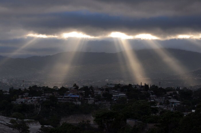 Sun rays appear through the clouds at daybreak in Tegucigalpa, Honduras, on May 17, 2010. (Photo: AFP)