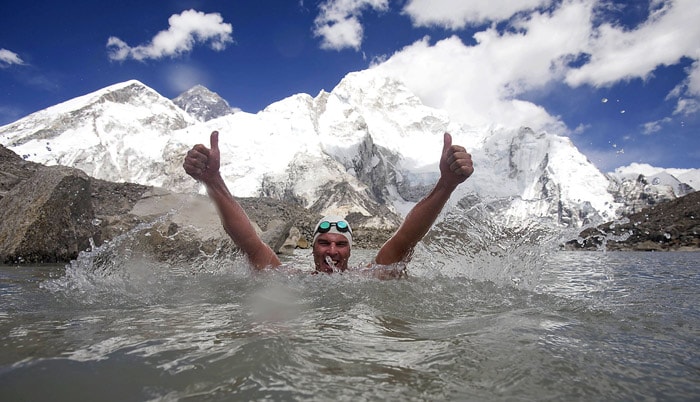 In this handout photograph released by Lewis Pugh via PlankPR on May 23, 2010, British environmental campaigner Lewis Pugh gestures after completing his swim in Lake Pumori at an altitude of 5,300 metres, below the summit of Mount Everest, on May 22, 2010.  Everest Ridge, Mount Everest and Mount Nuptse (L to R) can be seen in the background. An environmental campaigner has swum across a glacial lake on Mount Everest to highlight the impact of global warming, a report said. (Photo: AFP)