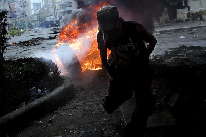 A Red Shirt anti-government protester runs after throwing a tyre into other burning ones on a street near Ding Daeng intersection in Bangkok on May 18, 2010. The Thai government said there would be no negotiations with protesters in the capital until they end their crippling rally, after a Senate offer to mediate crisis talks. (Photo: AFP)