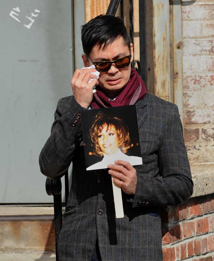 A fan wipes back tears at a memorial for singer Whitney Houston set up outside New Hope Baptist Church on February 17, 2012 in Newark, New Jersey.