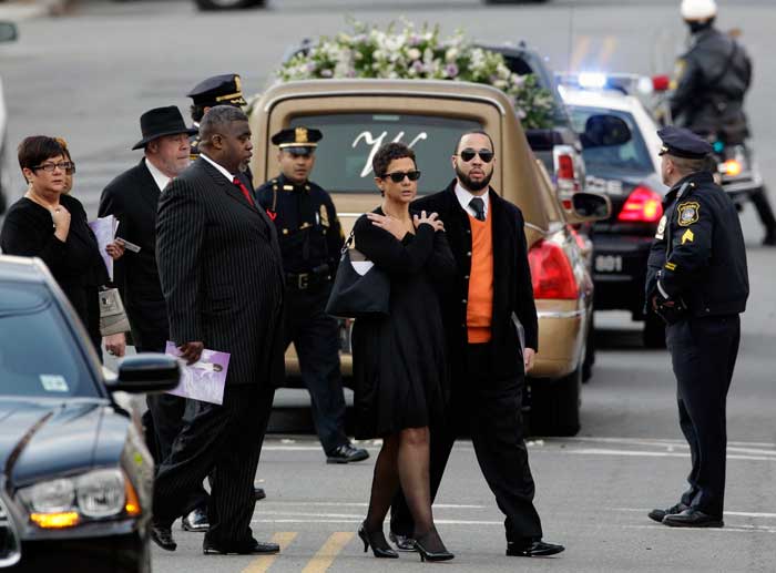 Mourners walk past the hearse with Whitney Houston's casket after her funeral at New Hope Baptist Church in Newark, N.J.