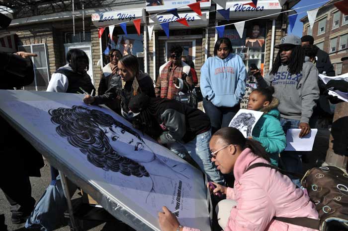 Fans sign a large poster while they gather on the streets near the New Hope Baptist Church as a private funeral for singer Whitney Houston is held at the church on February 18, 2012 in Newark, New Jersey.