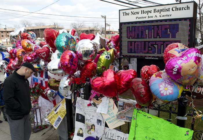 A man reads messages at Whitney Houston's memorial.