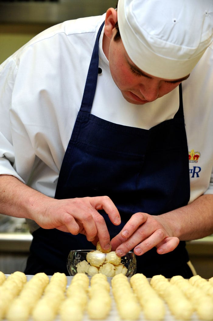 Royal Demi Chef De Partie, Shaun Mason, arranges handmade white chocolate truffles in a bowl.