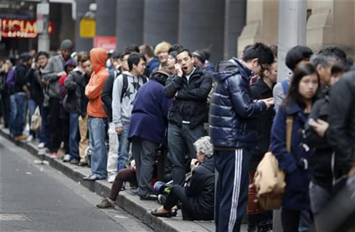 People queue outside an Apple store as they wait to buy an iPhone 5, in central Sydney.