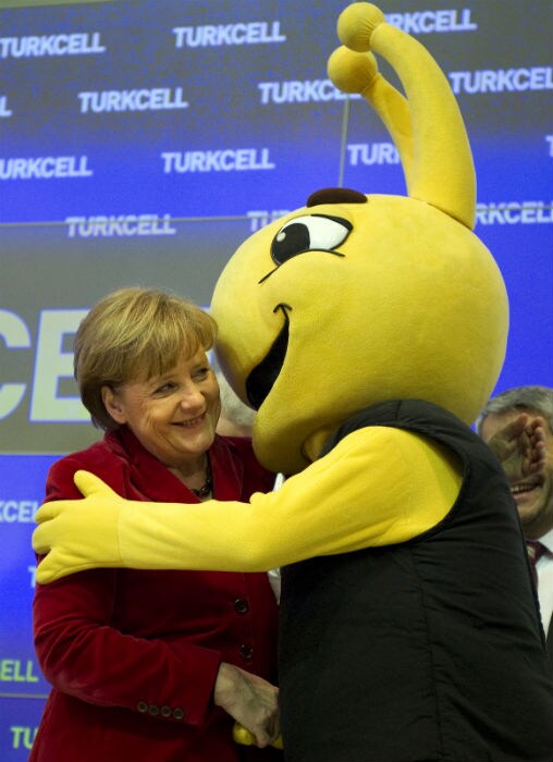 German Chancellor Angela Merkel is hugged by a mascot as she visits the stand of Turkish mobile phone operator Tukcell at CeBIT IT fair on its opening day. (Photo: AFP)