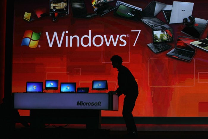 A worker moves a display of laptops on to the stage as Microsoft CEO Steve Ballmer delivers a keynote address at CES 2011.
