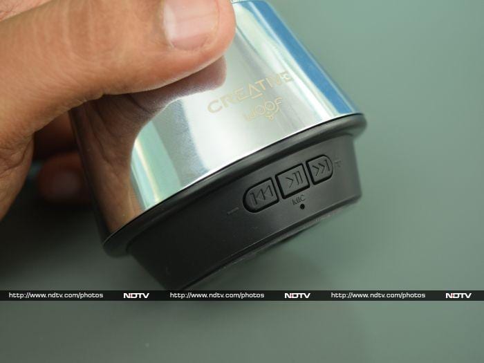 The control buttons are lined up on the black plastic strip below the metal speakers.