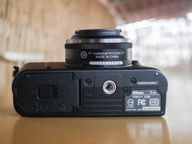 The lower part of Nikon V1 is smartly designed, housing the battery and memory card along with threaded hole for tripod mount