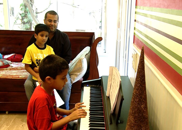 The writer looks at Shyam, while the latter tries to play piano.