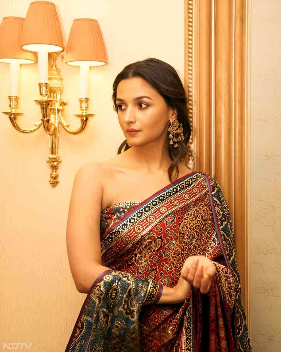 In a custom-made Abujani Sandeep Khosla ajrakh-print red-and-blue sari paired with a coordinating off-shoulder cape and a flowing train, Alia Bhatt showcased a stunningly ethereal festive fashion look. (Instagram/@aliaabhatt)