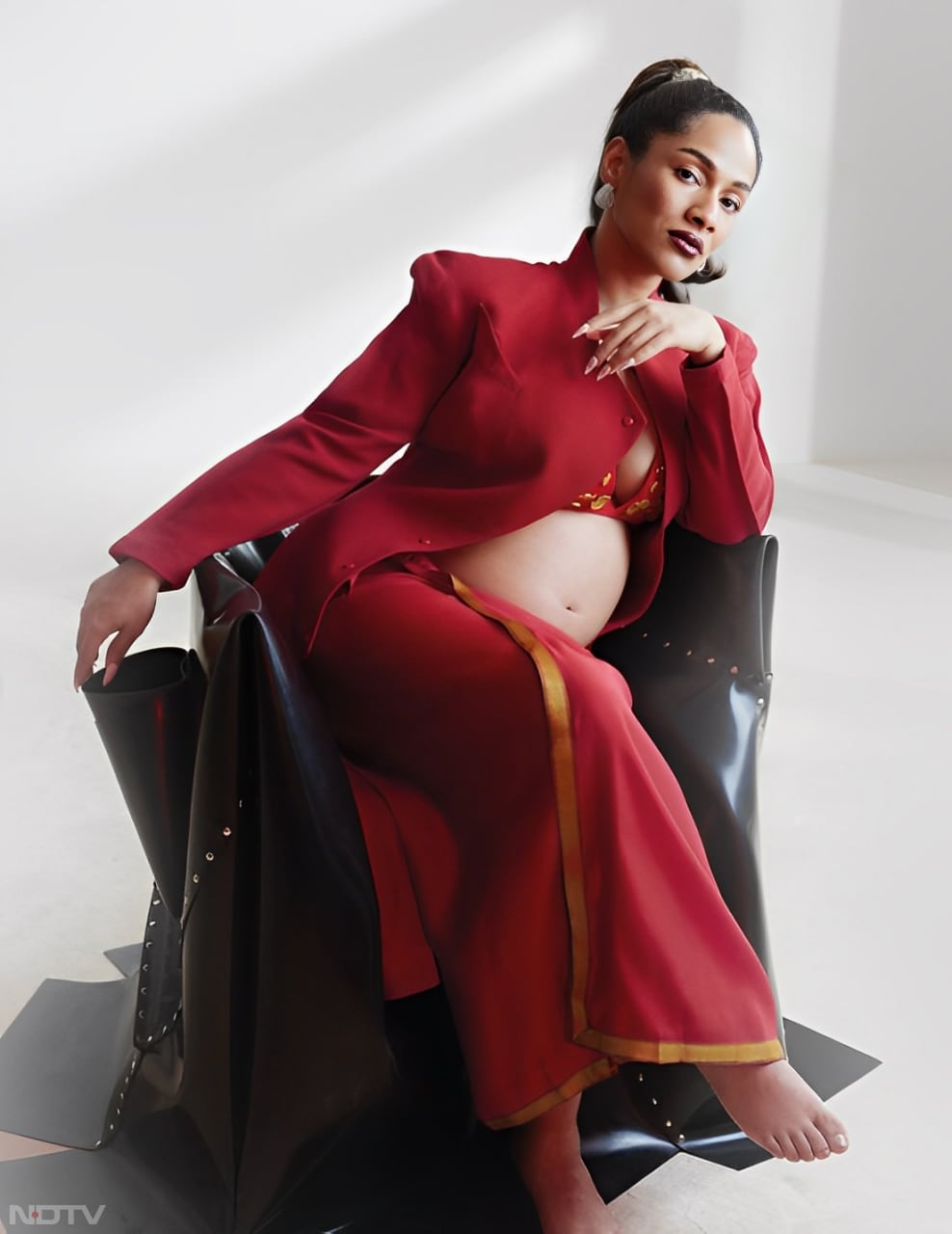 Fashion designer Masaba Gupta presented a regal maternity look in a striking red ensemble, featuring a bralette top with stunning gold detailing and a chic blazer. (Instagram/@masabagupta)