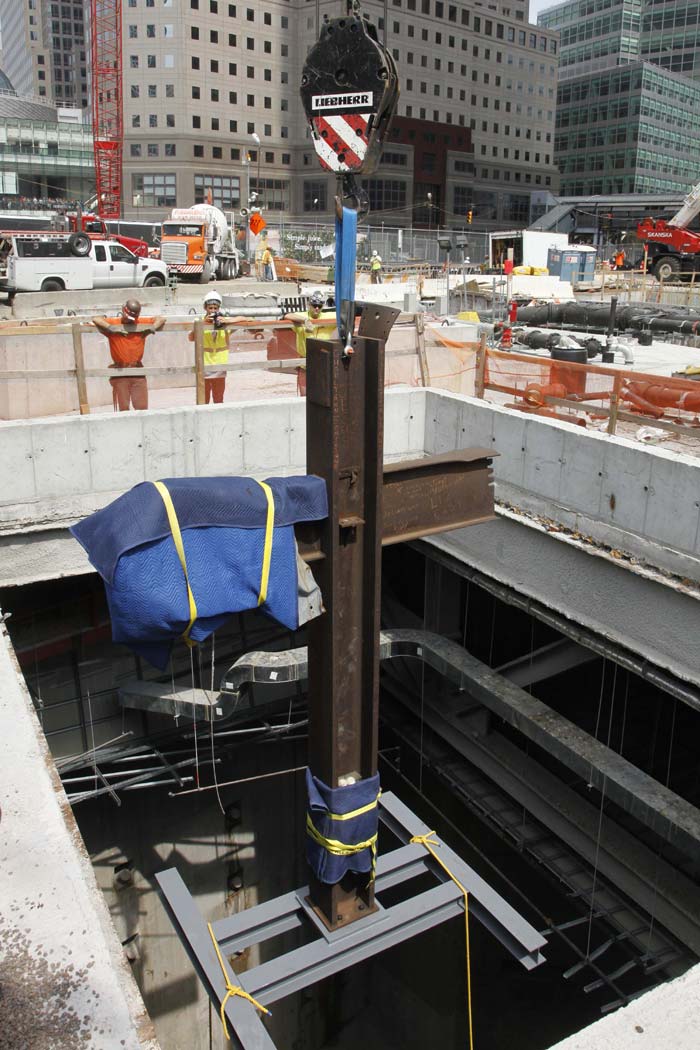 Construction workers lower the September 11 cross by crane into a subterranean section of the National September 11 Memorial and Museum on July 23, 2011 in New York City.<br><br>The cross is an intersecting steel beam discovered in the World Trade Center rubble which served as a symbol of spiritual recovery in the aftermath of 9/11. (AFP Photo)