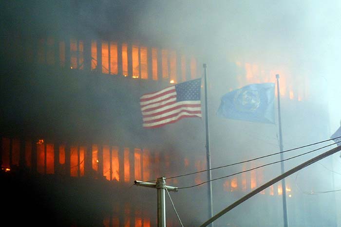 An American flag flies in the foreground as one of the twin towers at the World Trade Center burns in the background on September 11, 2001 in New York. (AFP Photo)