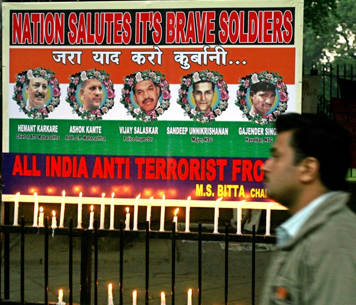 A man walks past candles placed before a poster bearing images of security forces personnel killed in the Mumbai attacks during a peace march in New Delhi on December 2, 2008. The march, one of at least three candle-lit memorials taking place in the Indian capital simultaneously, was held in memory of those killed in the mumbai attacks.(AFP photo)