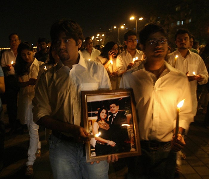 As seen in this photo, Karun and Nakul Agarwal walk with the photograph of their parents Sanjay and Rita Agarwal, during a candle light vigil outside the Oberoi Trident hotel. Their parents were amongst the victims killed in the dreadful attacks.(AFP photo)