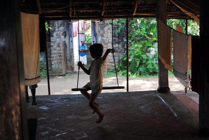 <b>Swinging with the times: </b>A child looks outside while sitting on a swing inside the house. (Image: Ketki Angre)