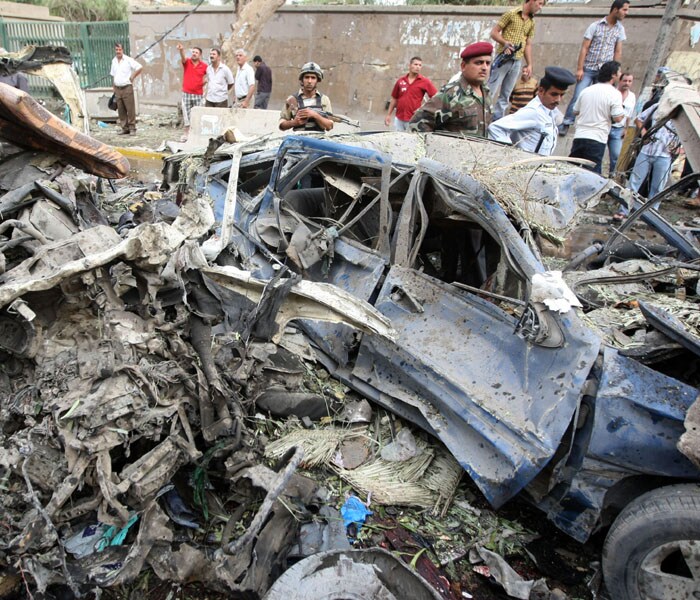 Iraqi security cordon off the wreckage of a vehicle following a suicide bombing outside the Baghdad Provincial Governorate in central Baghdad. At least 136 people have been killed in the two suicide bombings which rocked Baghdad. (AFP Photo)