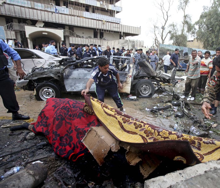 Iraqi men cover the bodies of victims killed by a massive bomb attack in Baghdad. Police say that a pair of powerful explosions rocked downtown. (AP Photo)