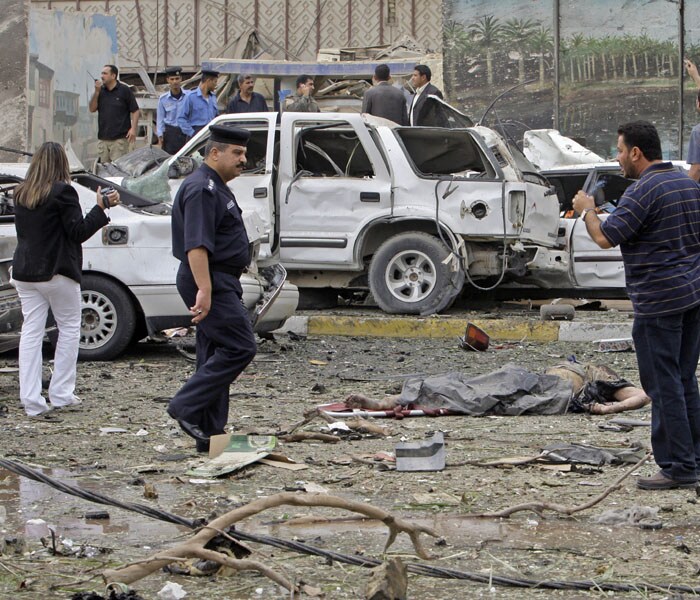 Iraqis gather next to the body of a victim killed by a massive bomb attack in Baghdad. (AP Photo)