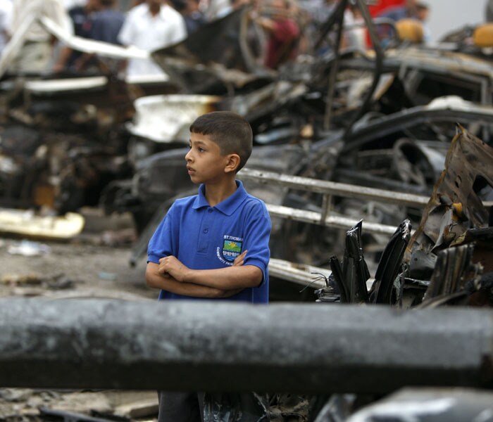 An Iraqi boy stands amongst the debris of destroyed vehicles strewn outside the ministries of justice and labour following a suicide bombing. (AFP Photo)