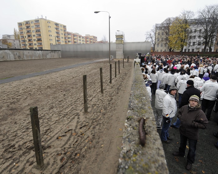 People gather behind the back wall (east side, looking west) of a preserved segment of the Berlin wall during a commemorative event to mark the 20th anniversary of the fall of the wall in Berlin. (AFP Photo)