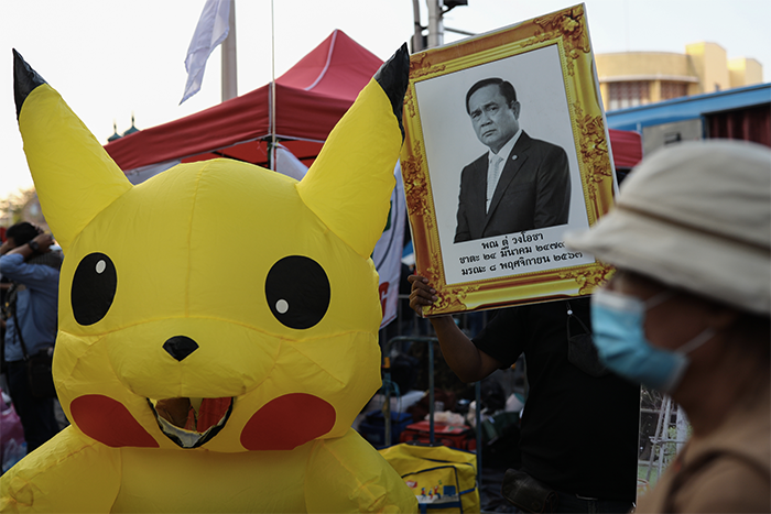 A pro-democracy protester holds up a portrait of Thailand's Prime Minister Prayut Chan-O-Cha as another dresses up as the Pokemon character Pikachu during a rally to denounce the use of the lese majeste law, under section 112 of the penal code, in Bangkok on December 10, 2020. (AFP)