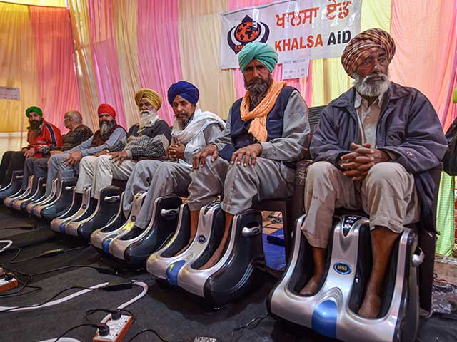 Farmers take foot massage, set up by an international NGO, at Singhu border during their sit-in protest against the Centre's farm reform laws, in New Delhi.