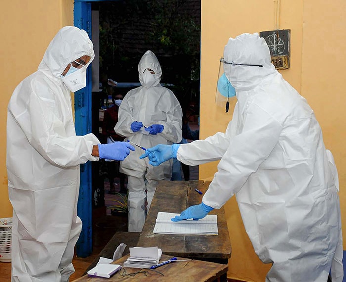 COVID-19 patients, wearing PPE kits, cast their vote during the last stage of local body elections at a government school, in Kozhikode.