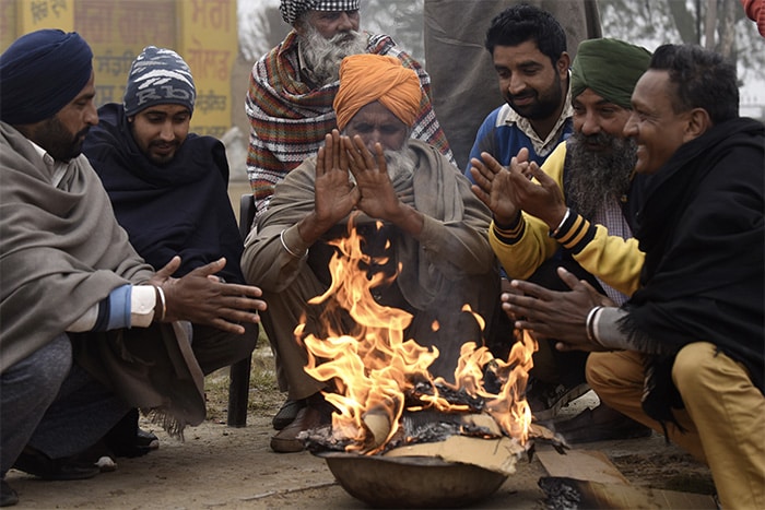 Villagers sit around a bonfire to warm themselves on a cold winter morning near the India-Pakistan Wagah Border Post.