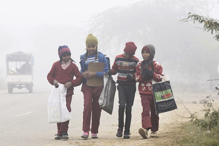 Children walk to their school amid dense fog on a cold winter morning near the India-Pakistan Wagah Border Post.