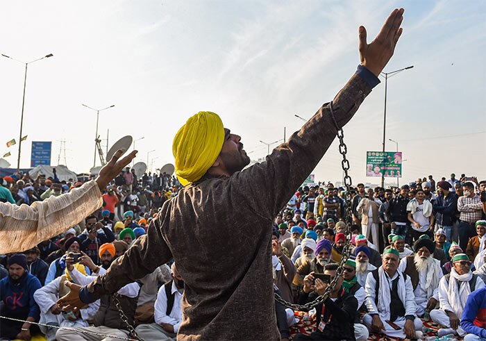 An artist performs while farmers block a road at Ghazipur border during their ongoing agitation againstthe farm reform laws, in New Delhi