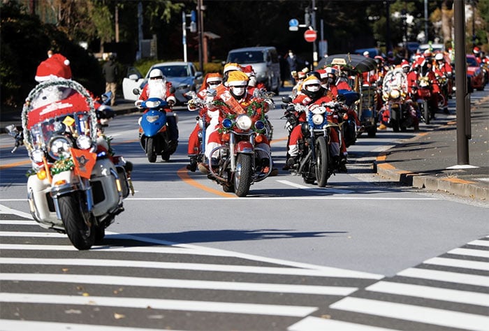 People in Santa Claus costumes ride their motorbikes during Xmas Toy Run parade against child abuse, organised by Harley Santa Club, amid the coronavirus disease in Tokyo