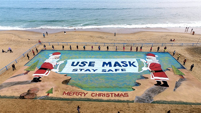 Sand artist Sudarsan Pattnaik creates a 3D sand Santa Claus with a message to use masks, on the eve of Christmas at Puri beach, Thursday.