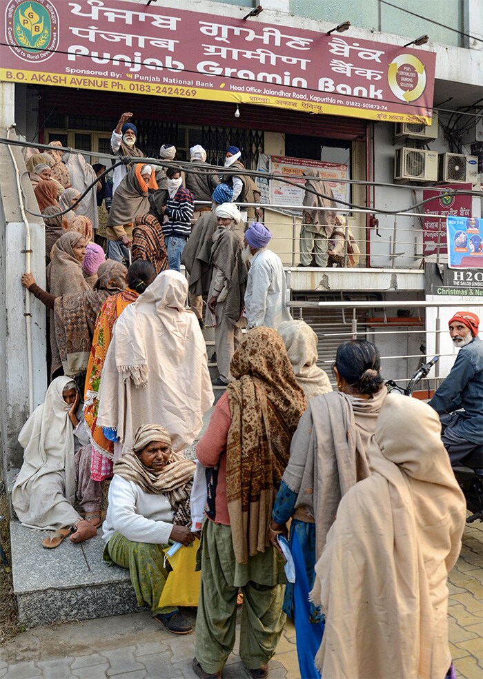 Senior citizens queue up outside a bank to receive their pension, during a cold day, in Amritsar.