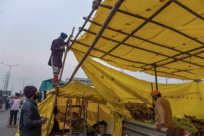 Farmers repair their makeshift tents on a rainy day, during the agitation against new farm laws, at Ghazipur border, in New Delhi.