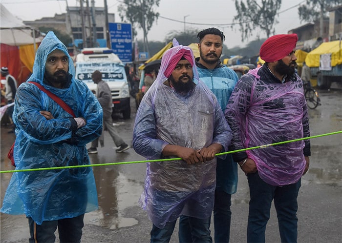 Farmers stand in rain during their ongoing protest against new farm laws, at Singhu border, in New Delhi.