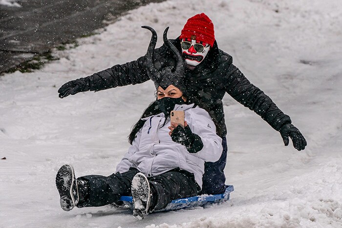 People ride on a sled amidst persistent snowfall on February 13, 2021 in Seattle, Washington. A large winter storm dropped heavy snow across the region.