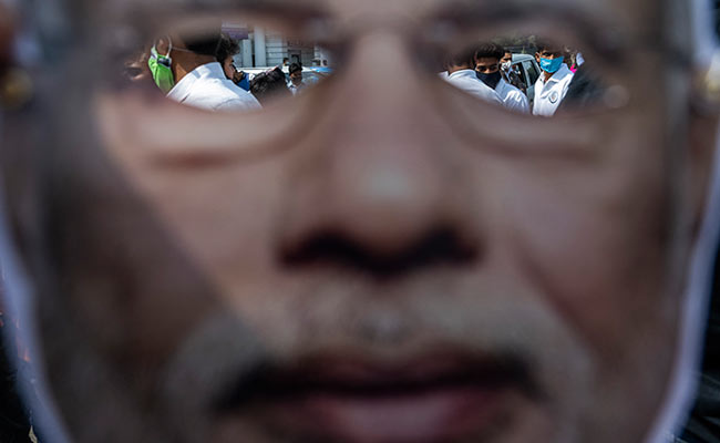 Indian Youth Congress activists and supporters are seen through a mask of PM Modi during a protest in Delhi.