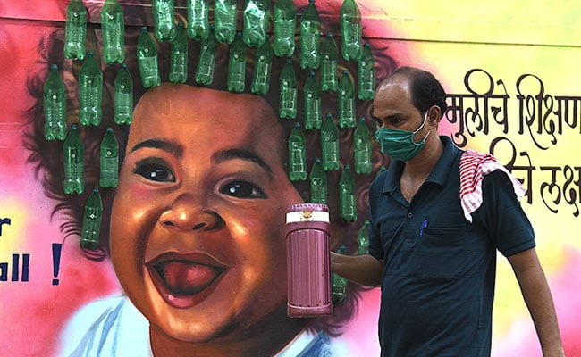 A man wearing a facemask walks past a mural after authorities imposed new restrictions as a preventive measure against the spread of Covid in Mumbai.