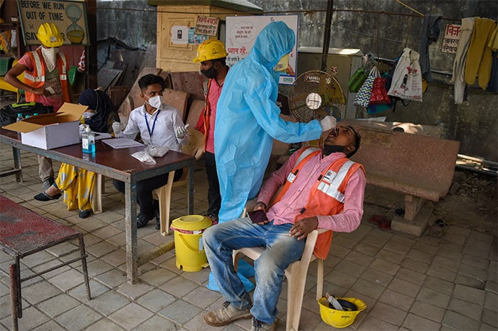 A health worker takes a swab samples of a labourer for coronavirus test in Mumbai