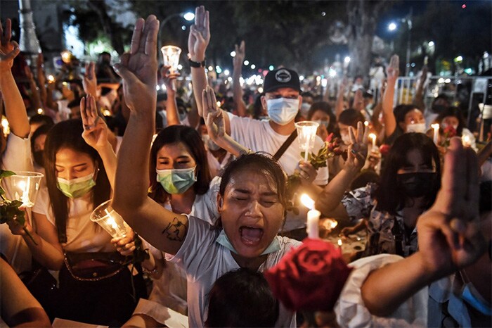 Myanmar migrants living in Thailand make the three-finger salute during a candlelight vigil at a memorial in Bangkok on March 4, 2021 to honour those who died during demonstrations against the military coup in their homeland.