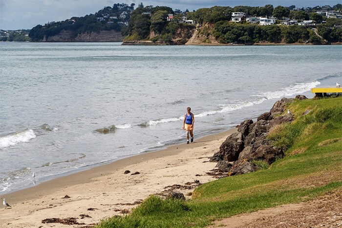 A lone person walks along a beach in Orewa, north of Auckland, on March 5, 2021, as tens of thousands of coastal residents in New Zealand, New Caledonia and Vanuatu fled for higher ground as a cluster of powerful earthquakes sparked a Pacific-wide tsunami alert.