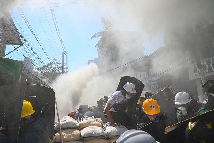 Protesters react after tear gas was fired during a demonstration against the military coup in Yangon on March 8, 2021.