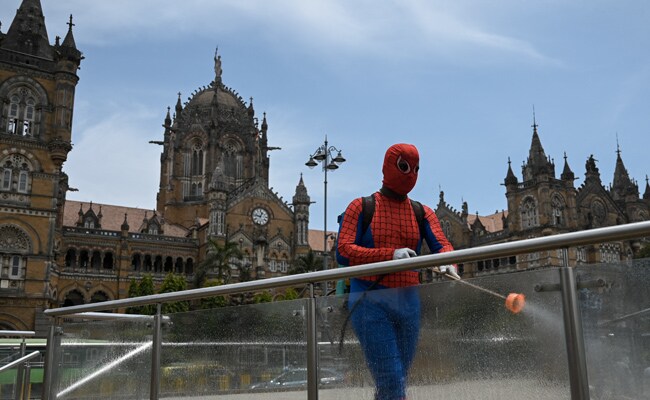 A pharmaceutical company employee, dressed as Spiderman sprays disinfectant outside Chhatrapati Shivaji Maharaj terminus in Mumbai.