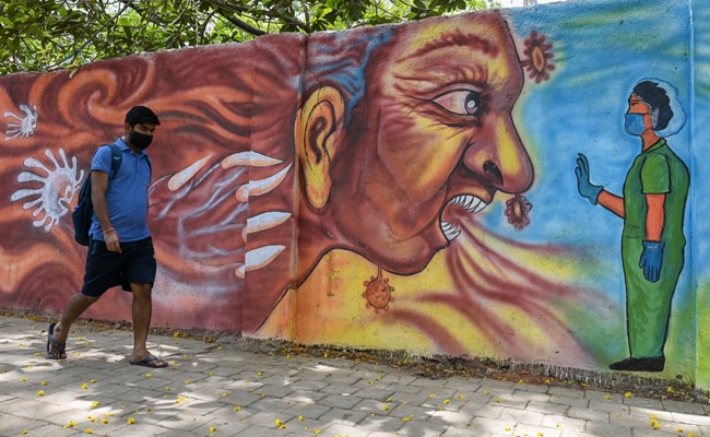 A pedestrian walks past a mural depiciting a health worker stopping Covid, in Mumbai.